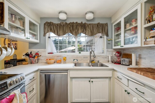 5418 Nootka Loop, Blaine, WA 98230 - kitchen with stainless steel appliances, a sink, decorative backsplash, light countertops, and glass insert cabinets