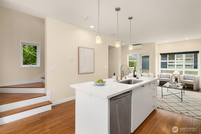 kitchen with a sink, a wall unit AC, wood finished floors, white cabinets, and recessed lighting