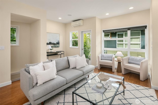 living area featuring an AC wall unit, baseboards, wood finished floors, and recessed lighting