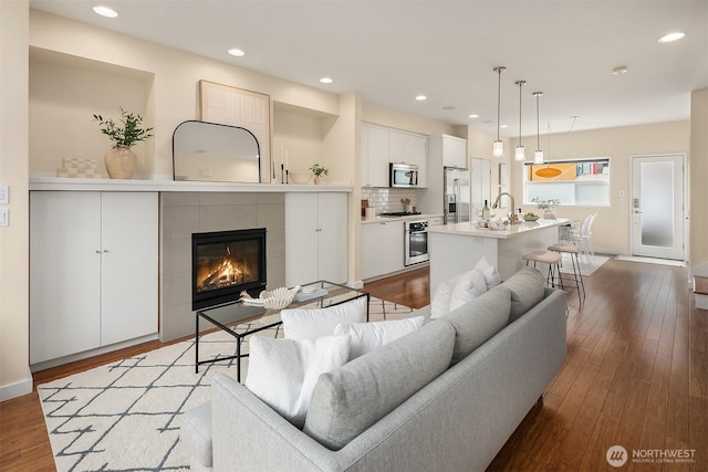 living area featuring a fireplace, wood finished floors, recessed lighting, and baseboards