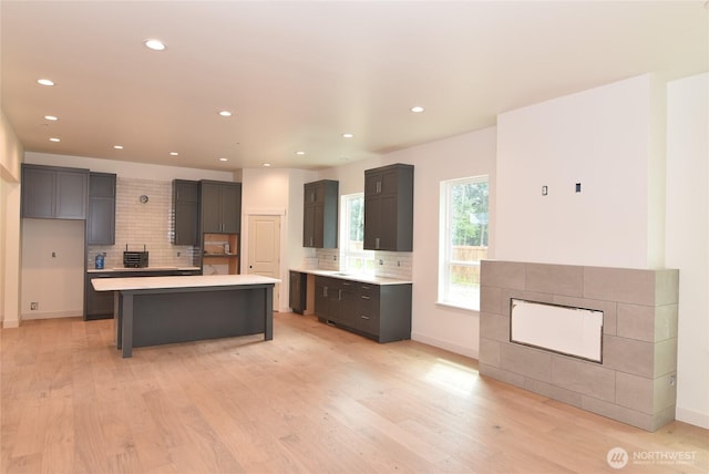 kitchen with decorative backsplash, light countertops, a kitchen island, light wood-style floors, and recessed lighting