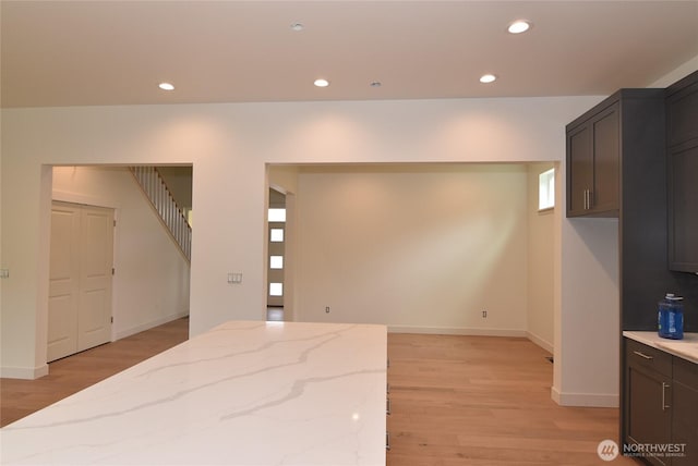 kitchen with light wood-type flooring, light stone countertops, recessed lighting, and baseboards