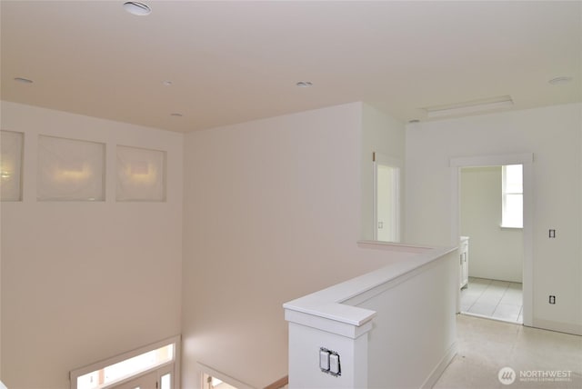corridor with an upstairs landing and light tile patterned floors