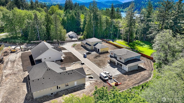 aerial view of property and surrounding area with a heavily wooded area and a mountain backdrop