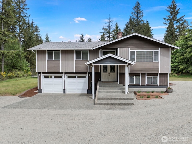 split foyer home with an attached garage, asphalt driveway, and a chimney