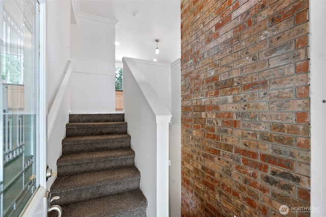 staircase featuring healthy amount of natural light and brick wall