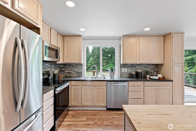 kitchen with appliances with stainless steel finishes, a sink, light brown cabinets, and recessed lighting