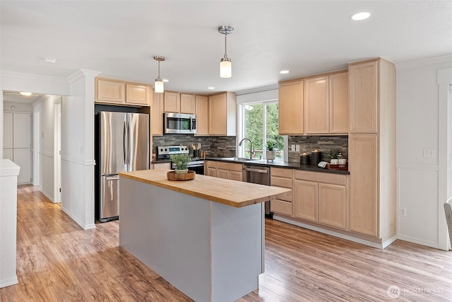 kitchen featuring stainless steel appliances, light brown cabinets, butcher block counters, a sink, and ornamental molding