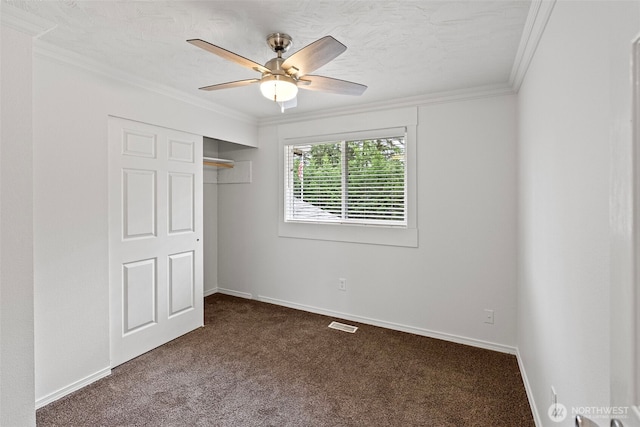 unfurnished bedroom featuring dark carpet, ornamental molding, a closet, baseboards, and a ceiling fan