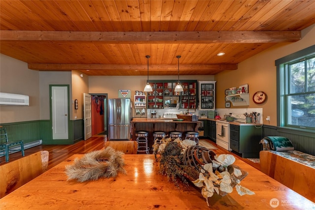 dining room featuring beam ceiling, a wainscoted wall, light wood finished floors, wooden ceiling, and a baseboard heating unit