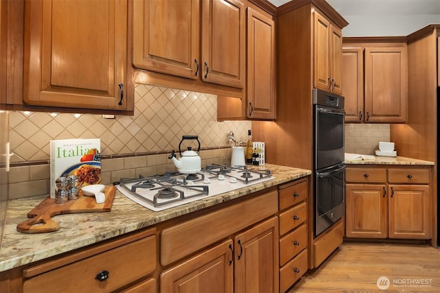 1118 2nd Ave S, Edmonds, WA 98020 - kitchen with stainless steel double oven, white gas cooktop, backsplash, light wood-style floors, and brown cabinetry