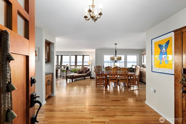 dining space with a chandelier, light wood-style flooring, plenty of natural light, and baseboards