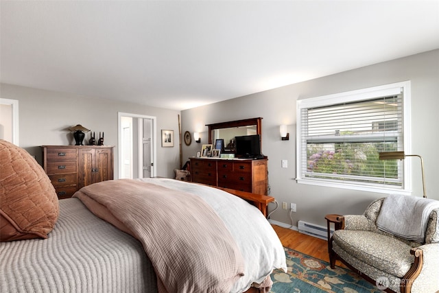 bedroom featuring baseboard heating, wood finished floors, and baseboards