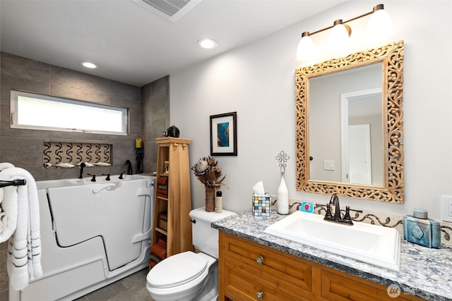 bathroom with a freestanding tub, vanity, toilet, and recessed lighting