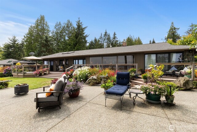 back of house with a fire pit, a patio, a wooden deck, a yard, and a chimney