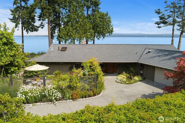 view of front facade with an attached garage, a water view, concrete driveway, fence, and board and batten siding