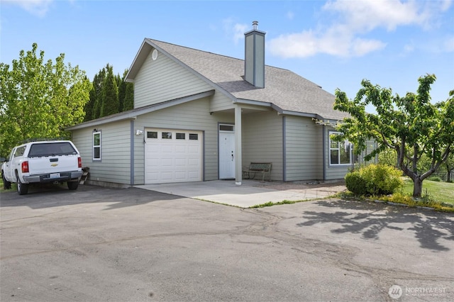 20501 Delta Rd NW, Soap Lake, WA 98851 - view of property exterior featuring a garage, a chimney, a shingled roof, and asphalt driveway