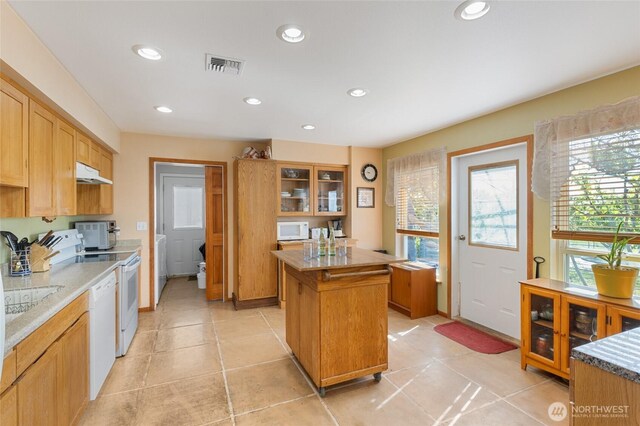 20501 Delta Rd NW, Soap Lake, WA 98851 - kitchen featuring under cabinet range hood, white appliances, a kitchen island, glass insert cabinets, and separate washer and dryer
