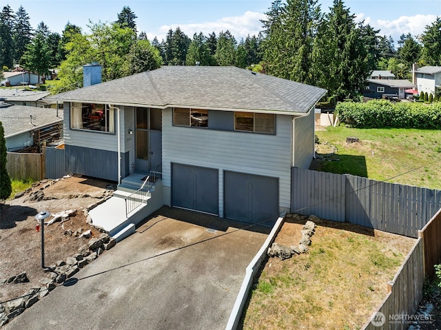 view of front facade with a garage, driveway, a chimney, and a shingled roof