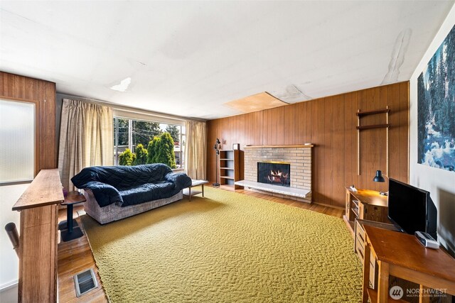 living area featuring wood finished floors, a brick fireplace, and wooden walls
