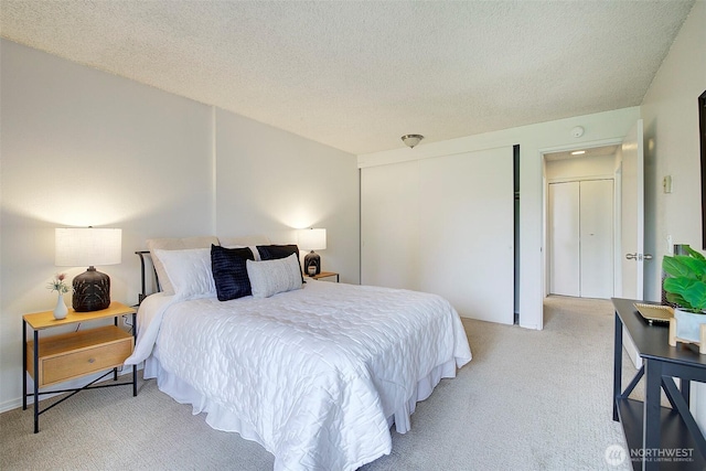 bedroom with light colored carpet and a textured ceiling