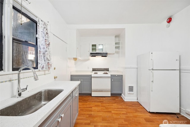 kitchen with white appliances, gray cabinets, a sink, extractor fan, and light wood-style flooring