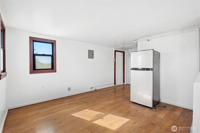 empty room featuring electric panel, light wood-style floors, and baseboards