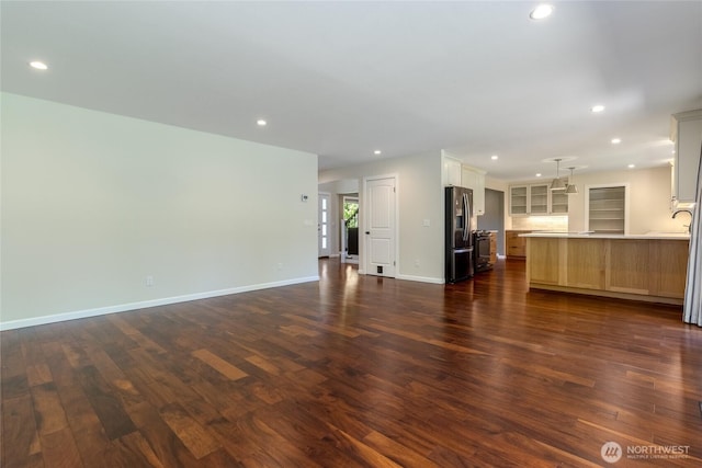 unfurnished living room featuring dark wood finished floors, recessed lighting, and baseboards
