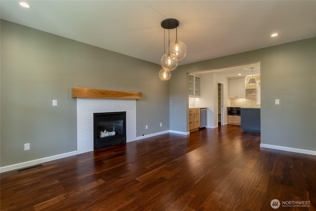 unfurnished living room with dark wood-style floors, baseboards, wine cooler, a fireplace, and recessed lighting