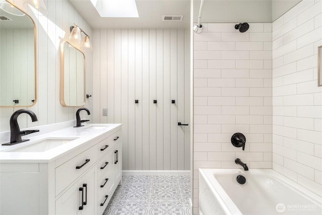 bathroom with bathtub / shower combination, double vanity, baseboards, and a skylight