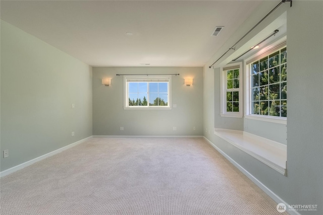 spare room featuring light colored carpet and baseboards