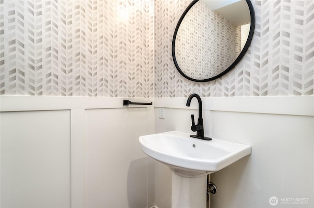 bathroom with wallpapered walls and a sink