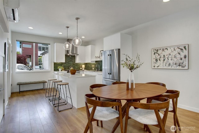 dining area with light wood-style flooring, baseboards, and recessed lighting