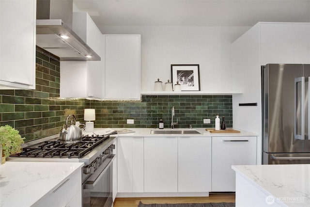 kitchen featuring appliances with stainless steel finishes, wall chimney exhaust hood, a sink, and white cabinetry