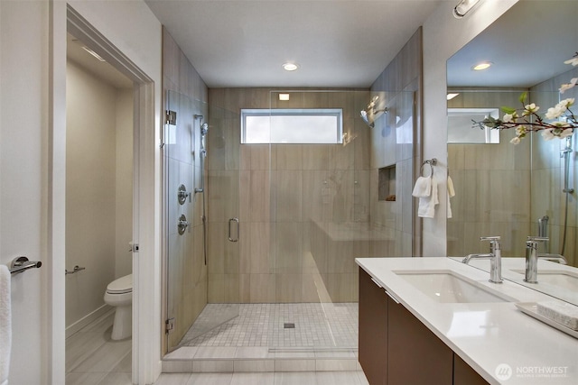 bathroom featuring toilet, a shower stall, and vanity