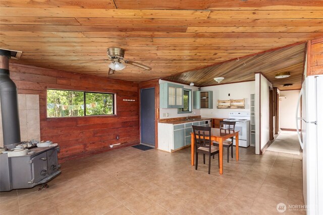 660 Schwartz Rd, Nordland, WA 98358 - dining space with a wood stove, wood walls, ceiling fan, wood ceiling, and light tile patterned flooring