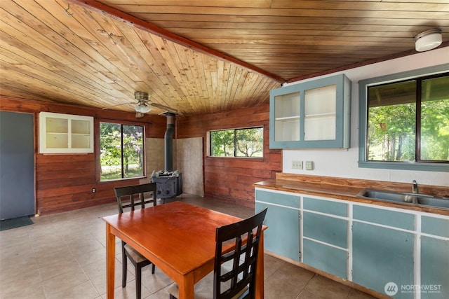 660 Schwartz Rd, Nordland, WA 98358 - dining area with wood ceiling, wooden walls, a wood stove, light tile patterned flooring, and ceiling fan