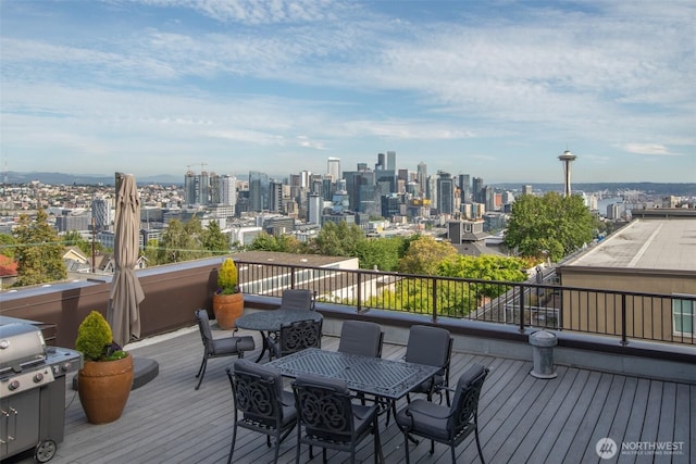 deck featuring a view of skyline, a grill, and outdoor dining area