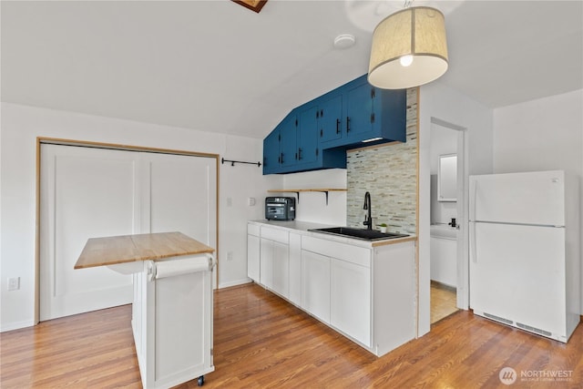 9320 96th St NE, Arlington, WA 98223 - kitchen featuring freestanding refrigerator, blue cabinetry, a sink, backsplash, and light wood-style flooring
