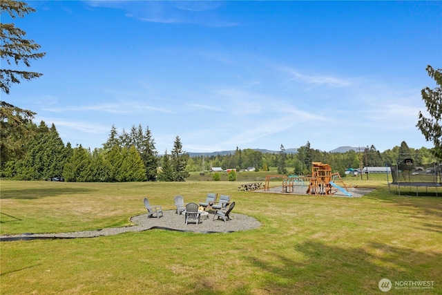 9320 96th St NE, Arlington, WA 98223 - view of playground with a trampoline, a fire pit, a mountain view, and a lawn