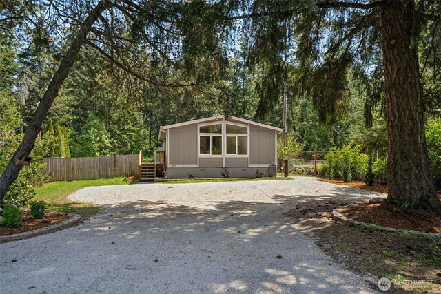 view of front of home with fence, driveway, and crawl space