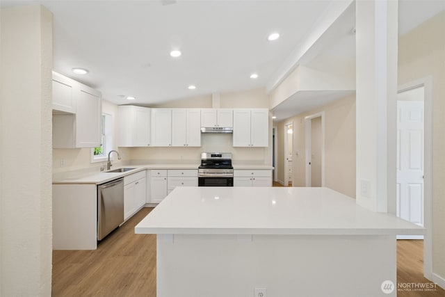 kitchen with appliances with stainless steel finishes, a sink, under cabinet range hood, light wood finished floors, and white cabinetry
