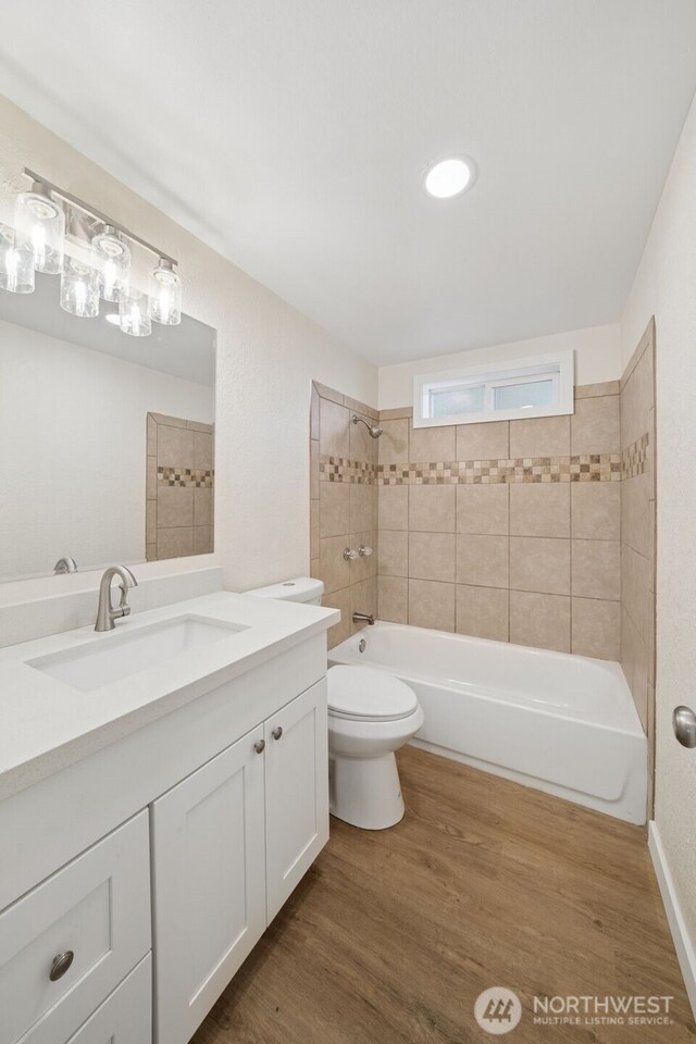 bathroom featuring bathing tub / shower combination, toilet, vanity, and wood finished floors
