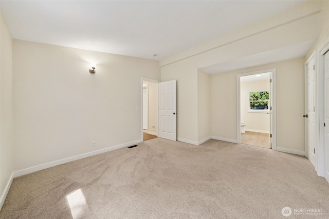 unfurnished bedroom with carpet floors, baseboards, and ensuite bath