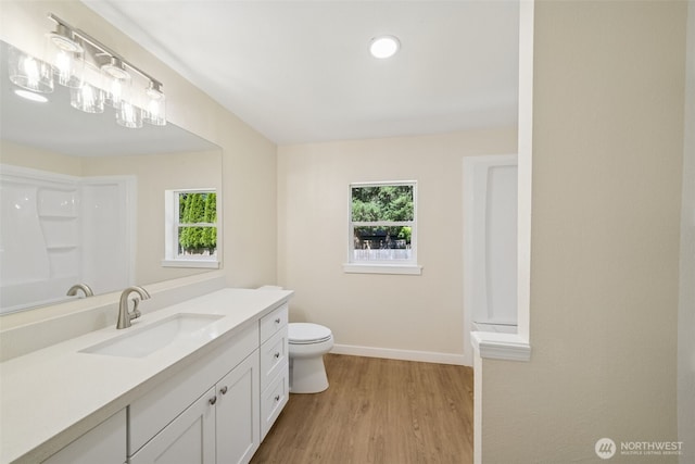 full bath with plenty of natural light, vanity, wood finished floors, and baseboards