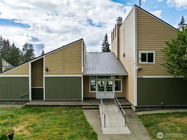 view of front of house featuring french doors, a front yard, and metal roof