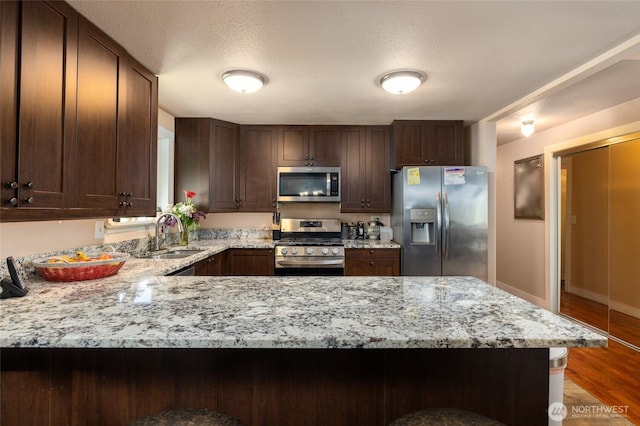 2809 E Sunset, Bellingham, WA 98226 - kitchen with appliances with stainless steel finishes, a peninsula, dark brown cabinetry, a textured ceiling, and wood finished floors