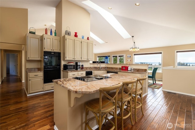 987 NW Camano Dr, Camano Island, WA 98282 - kitchen with black appliances, a skylight, light countertops, a peninsula, and a kitchen bar