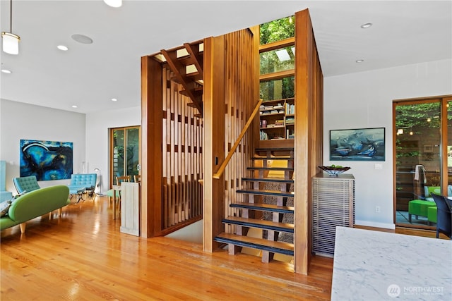 staircase featuring wood finished floors, plenty of natural light, and recessed lighting