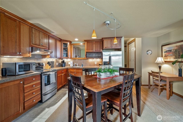7806 Birch Bay Dr Unit 515, Blaine, WA 98230 - kitchen with appliances with stainless steel finishes, under cabinet range hood, brown cabinets, and decorative backsplash